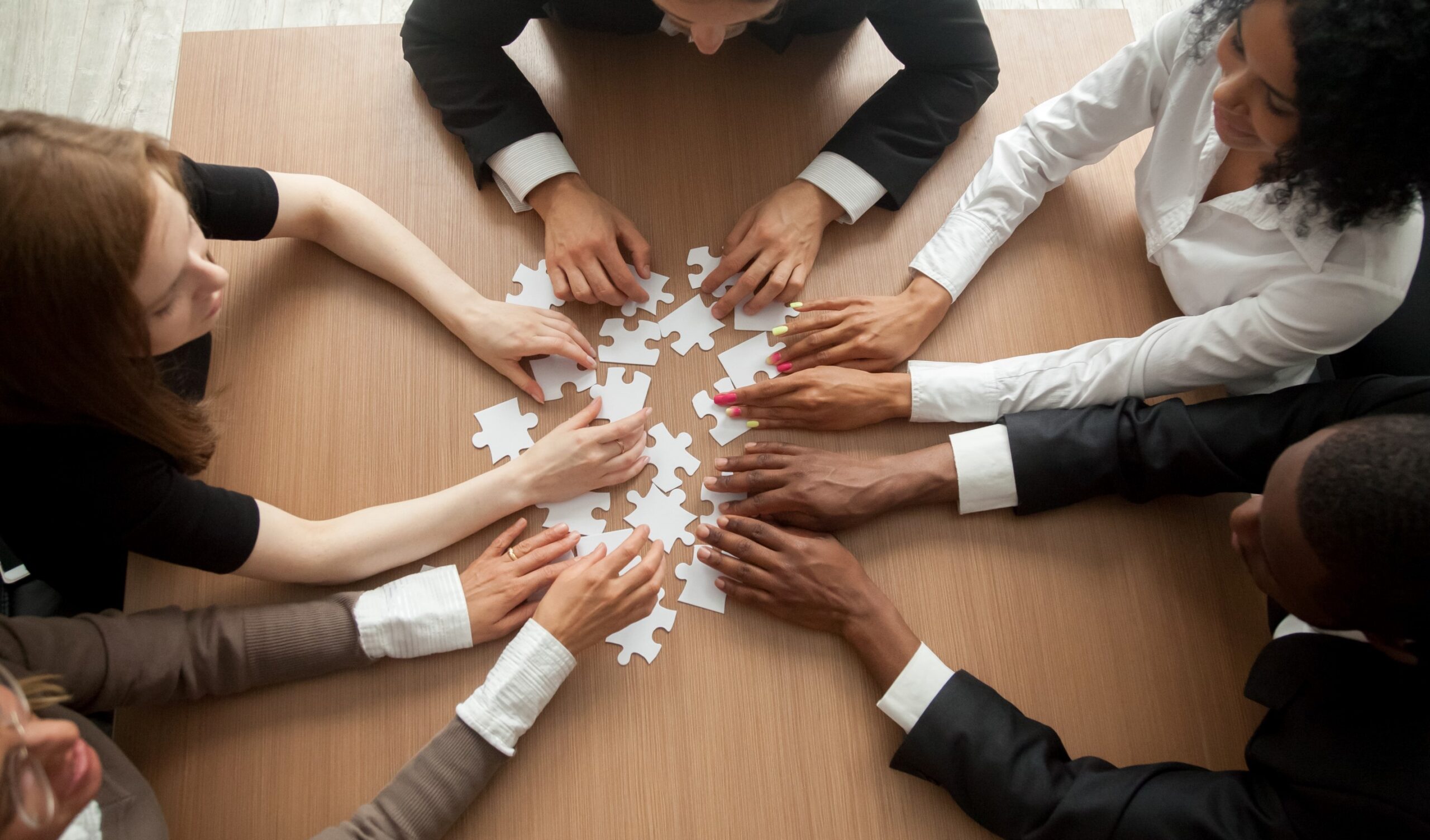 5 people at a table working on a puzzle